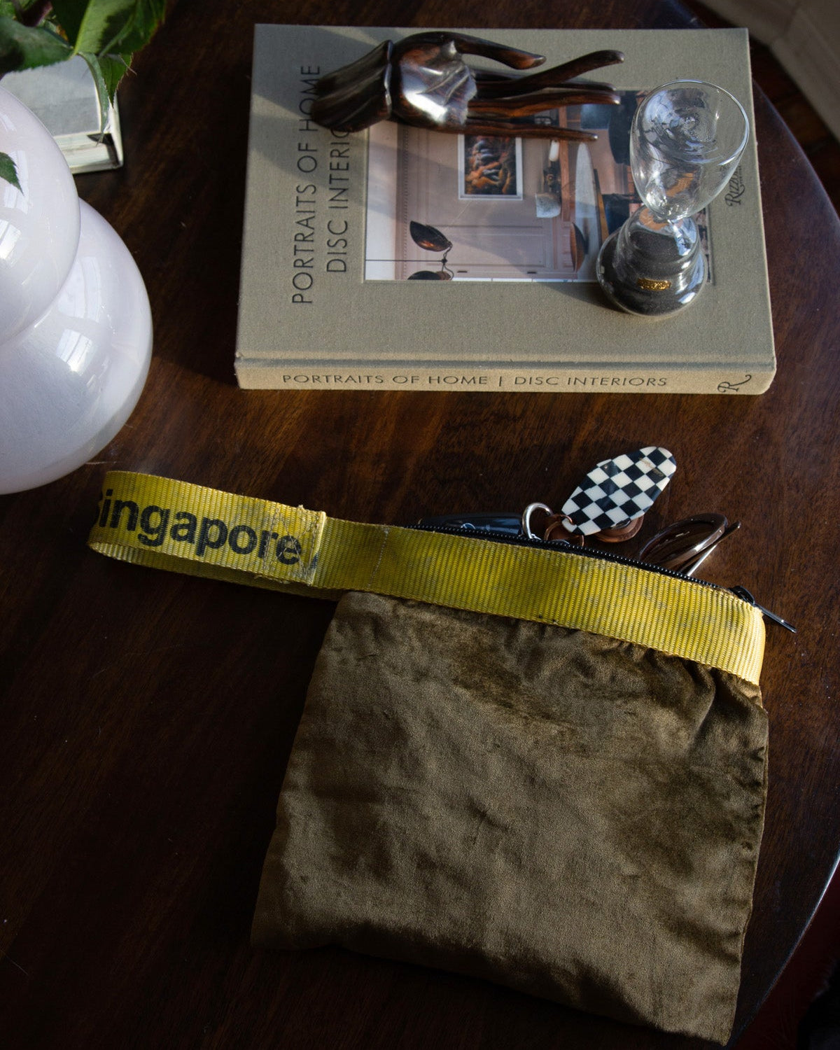 Book titled 'Portraits of Home' with a velvet pouch and keys on a wooden table.
