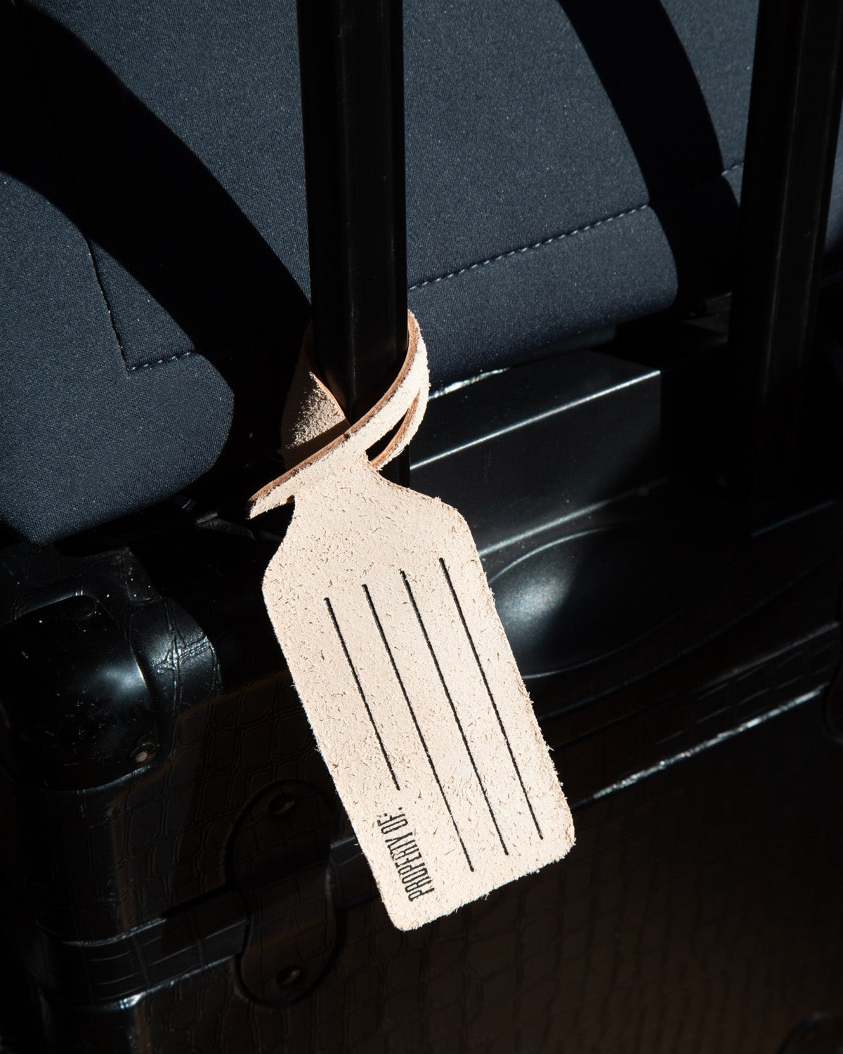 Leather luggage tag attached to a suitcase with a dark background