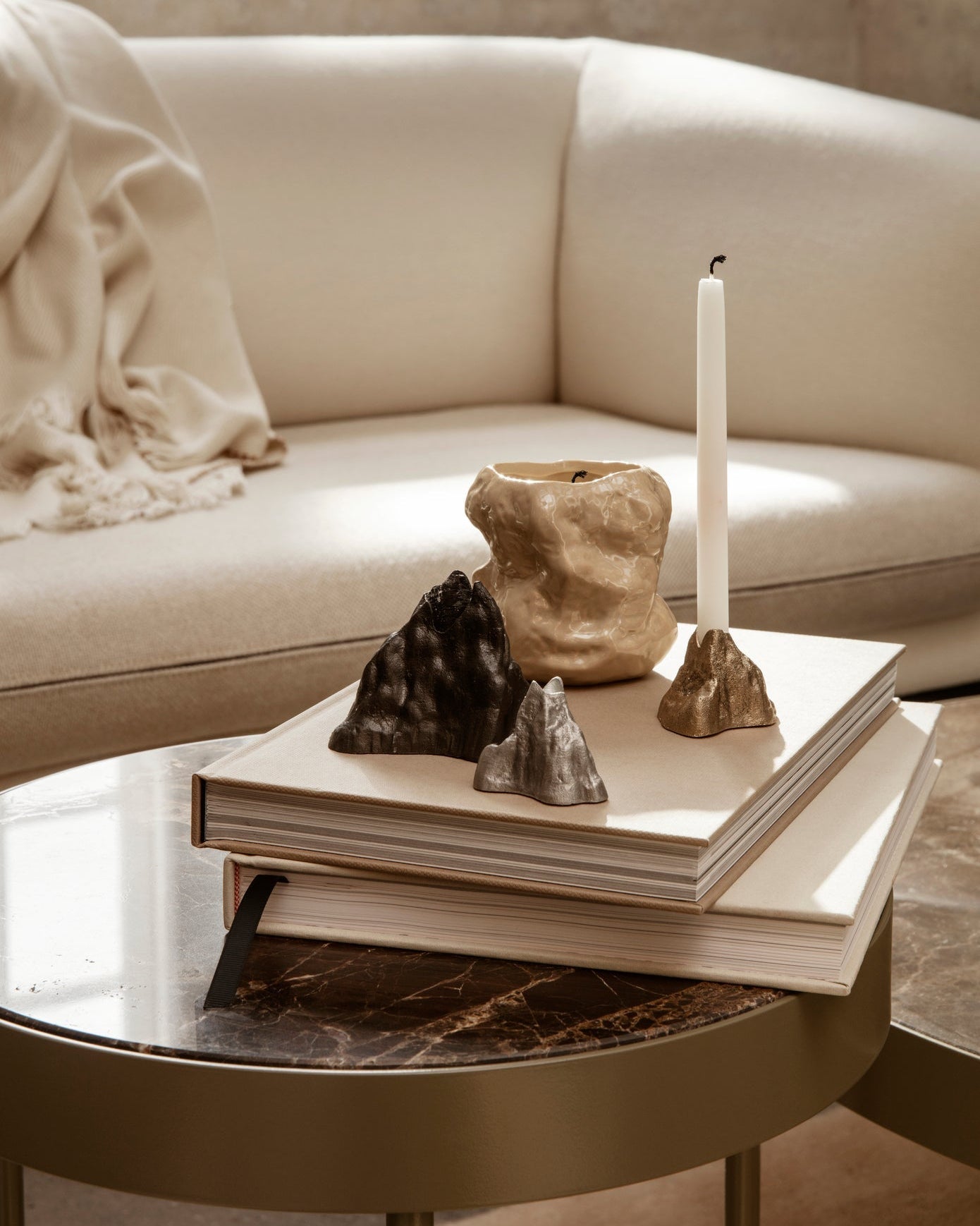 Decorative cast metal candle holders on a coffee table with a beige sofa in the background