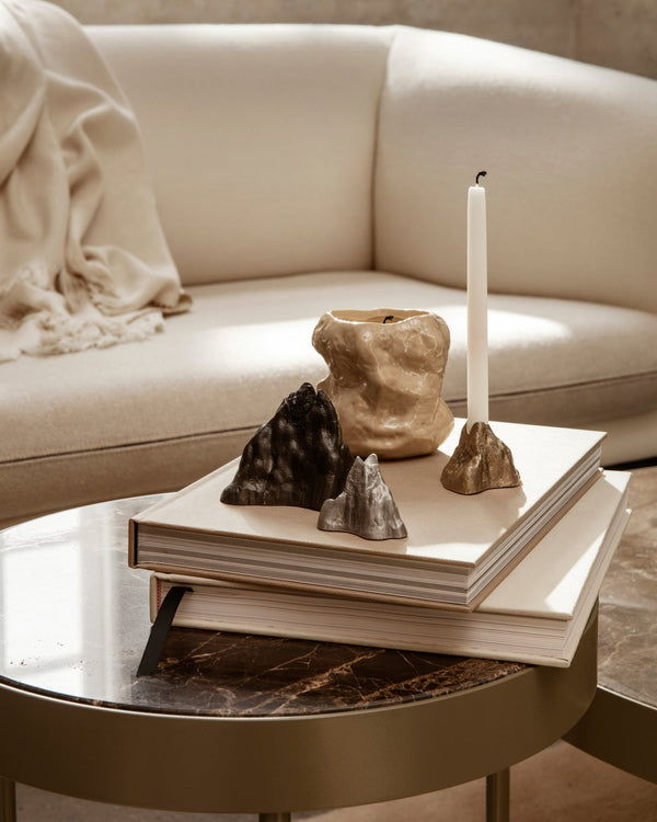 Decorative cast metal candle holders on a coffee table with a beige sofa in the background