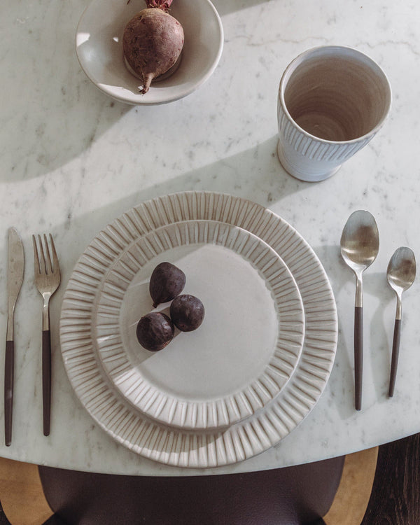 Dinner setting with a plate, cup, and cutlery on a marble surface
