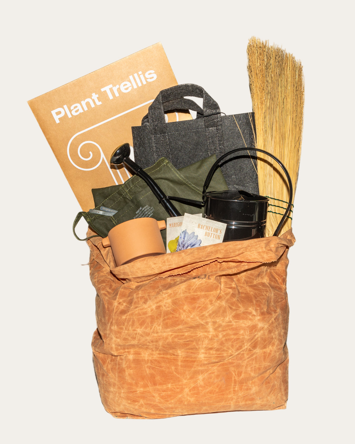 Brown bag with gardening items including a plant trellis, watering can, and broom on a white background