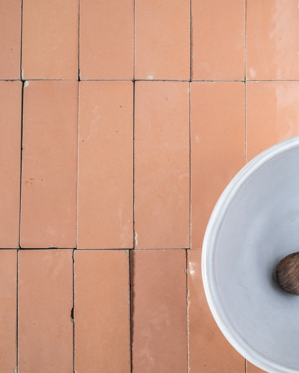 Coral Glazed Zelige tiles on a floor with a white bowl and brown object.