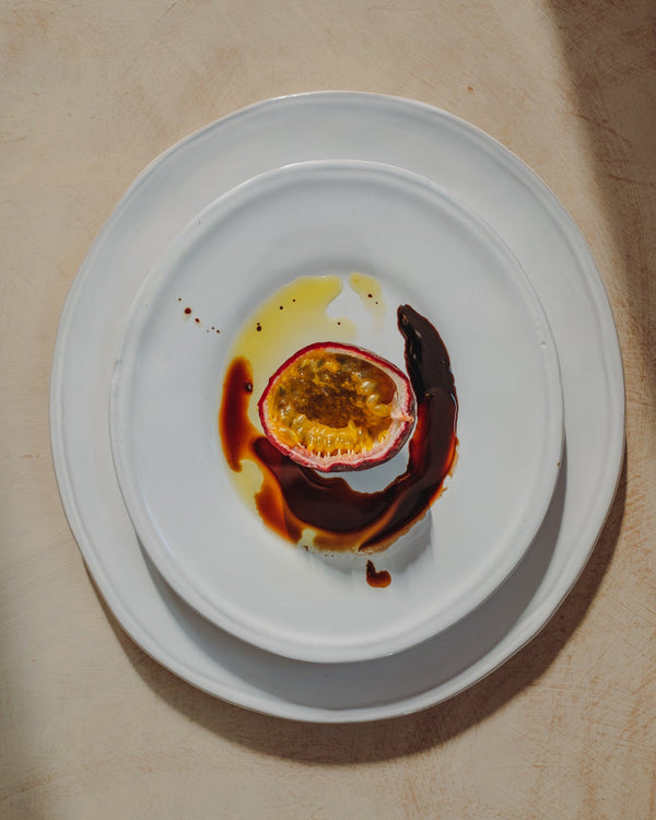 Half-eaten passion fruit with chocolate sauce on a white plate