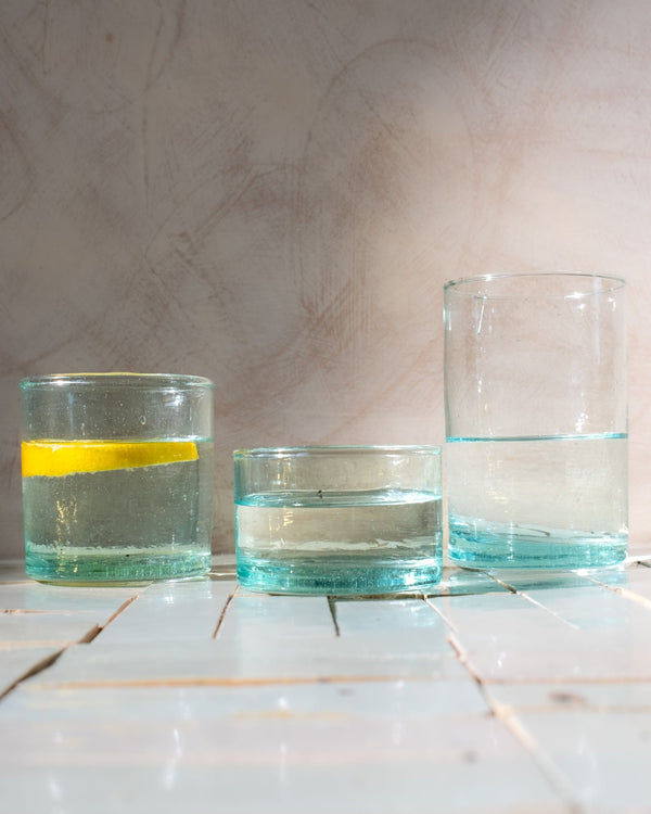 Three glass containers with water on a tiled surface