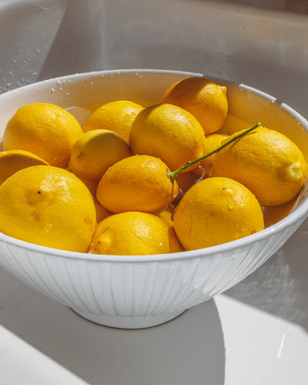White bowl filled with lemons in a sink