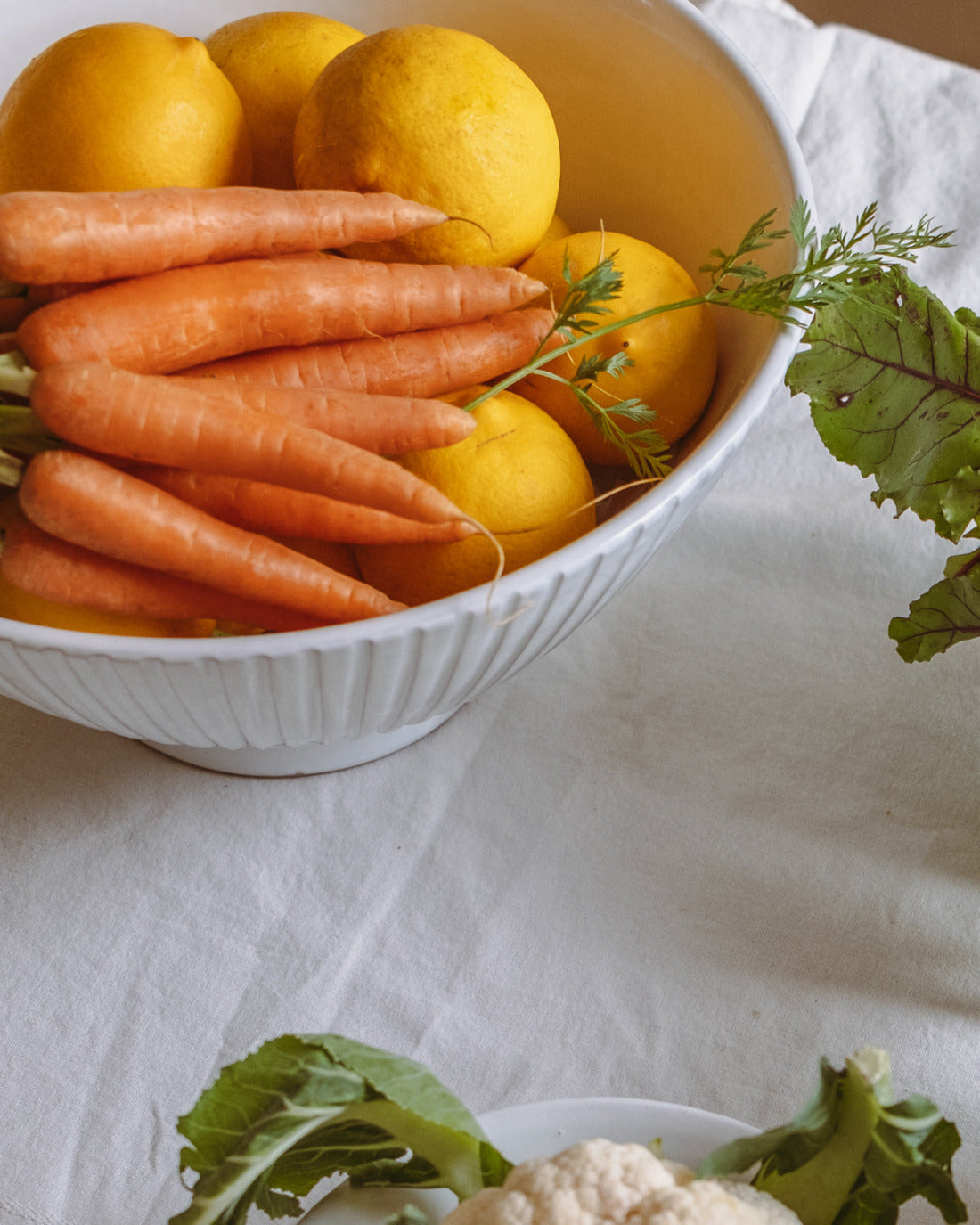 Bowl of carrots and lemons on a white tablecloth