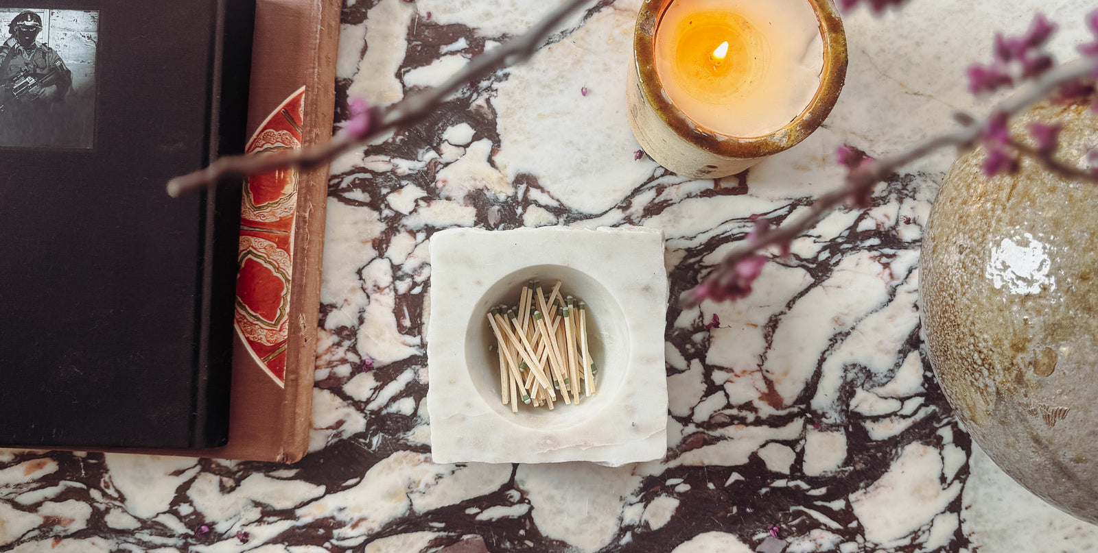 Candle, matches, and a book on a marble surface
